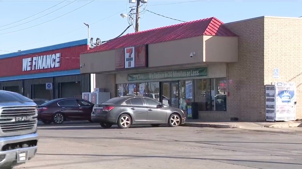 A street view showing a 7-Eleven store with a red roof next to a "WE FINANCE" business, with cars parked in front of both.